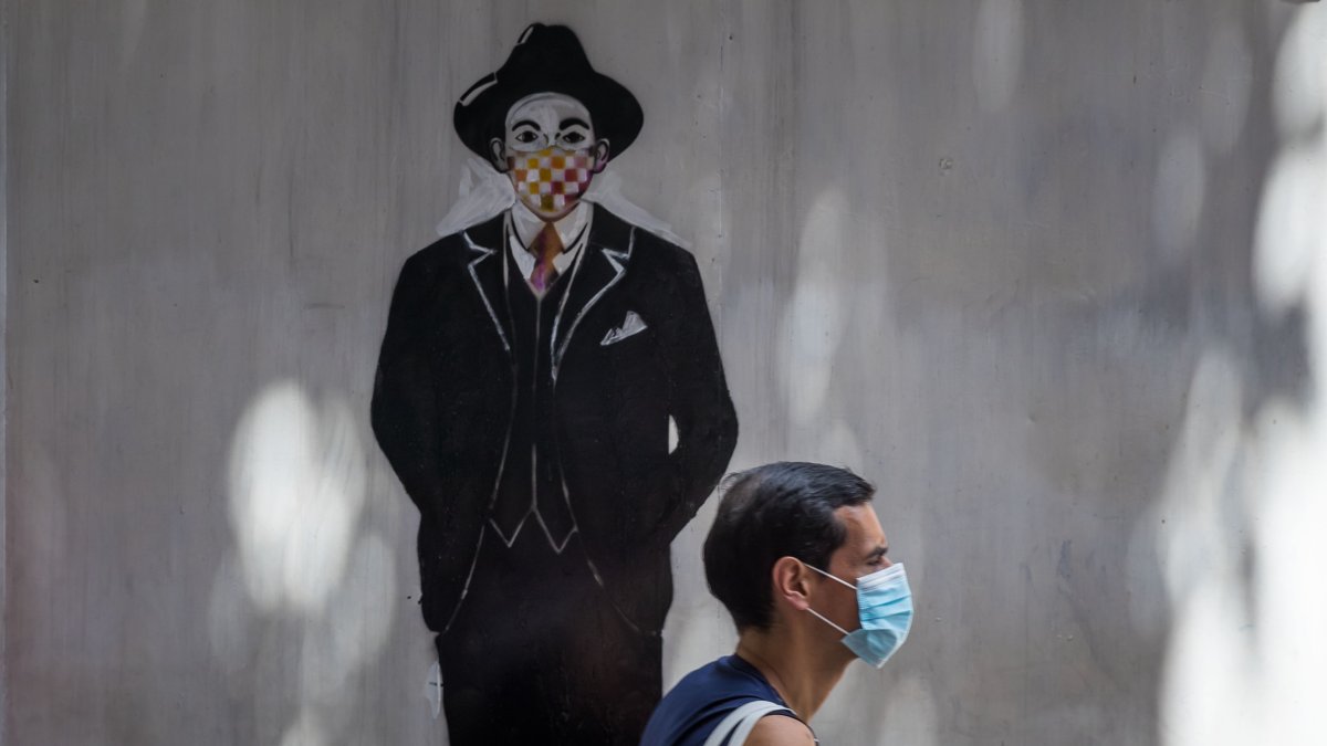 Una persona pasa frente a un mural de José Gregorio Hernández durante una ceremonia de exhumación de los restos del mismo, en las inmediaciones de la iglesia de Nuestra Señora de La Candelaria, en Caracas.