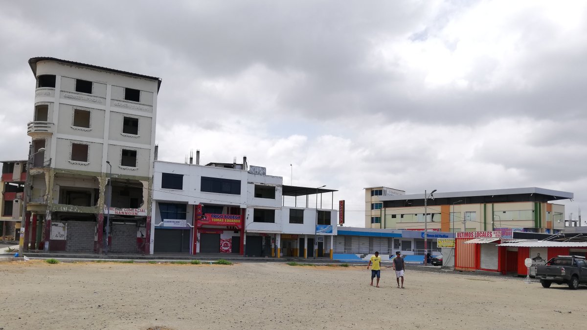 Moradores de Tarqui pasan por el terreno donde antes se ubicaba el mercado que se destruyó con el terremoto de 2016.
