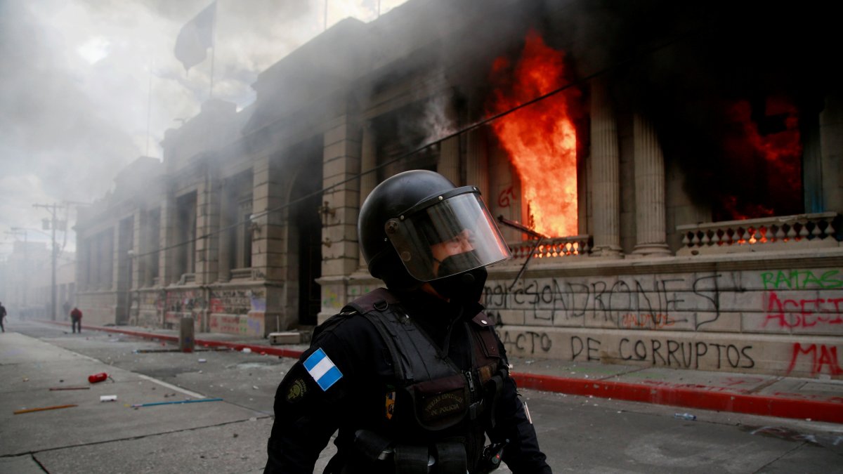 Un policía camina junto al fuego desatado, el 21 de noviembre de 2020, en el Congreso en Ciudad de Guatemala durante una jornada de protestas.