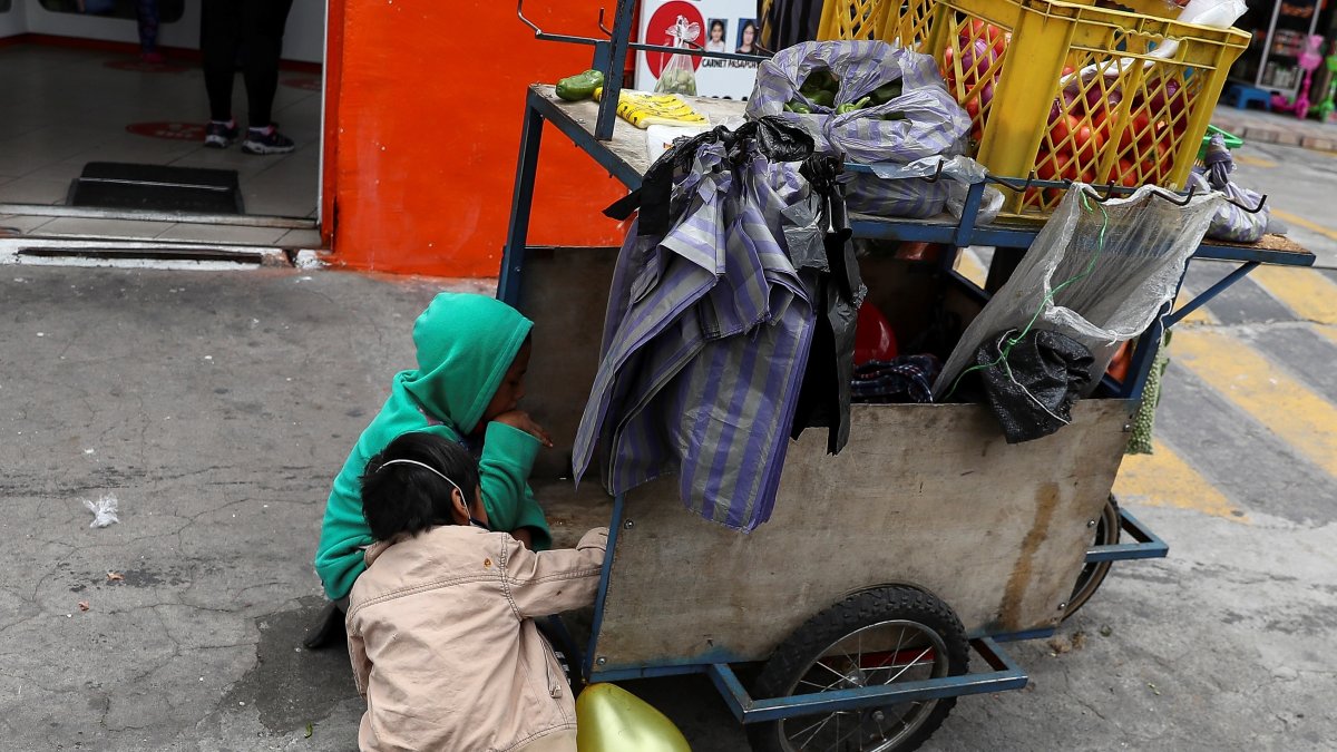 Fotografía de archivo donde se observan niños que acompañan a sus padres a trabajar con una carreta de productos vegetales en una calle de Quito.
