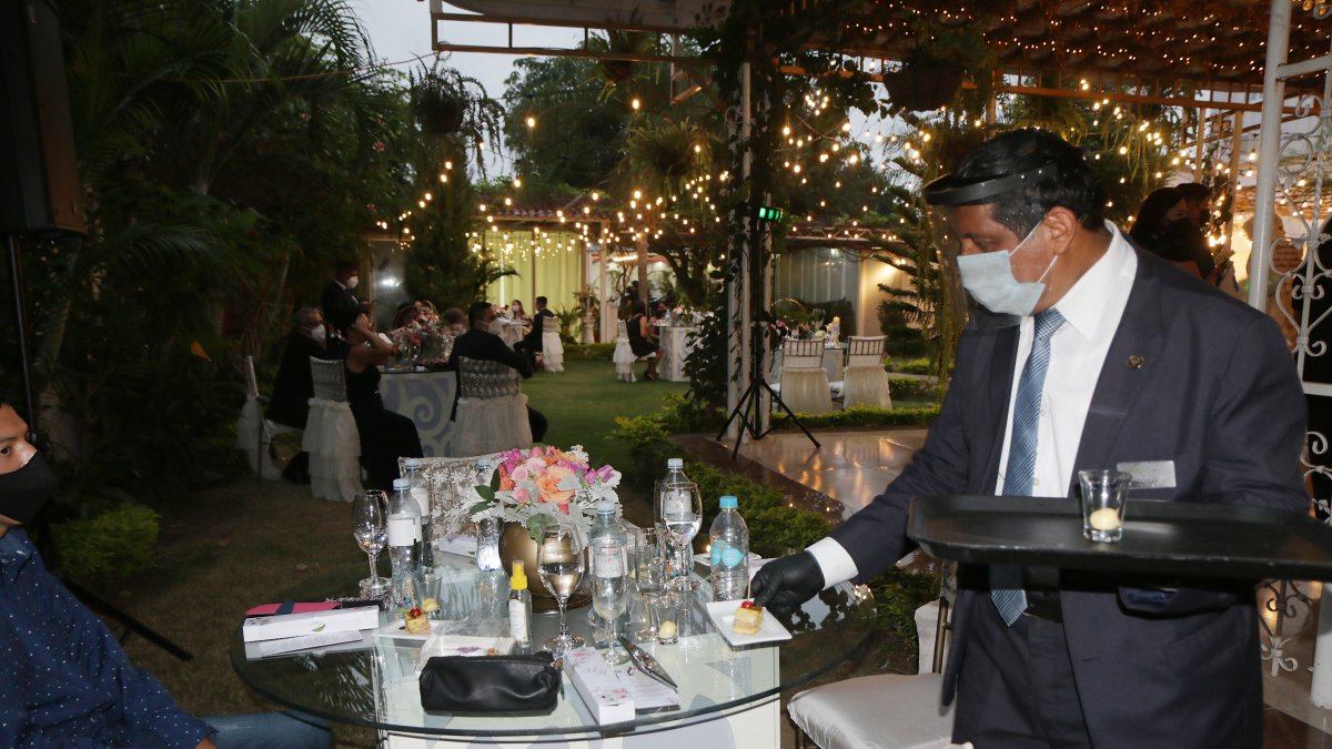 En esta fiesta se observan las mesas separadas, el bocadillo personal y cómo está la persona que está sirviendo los alimentos.