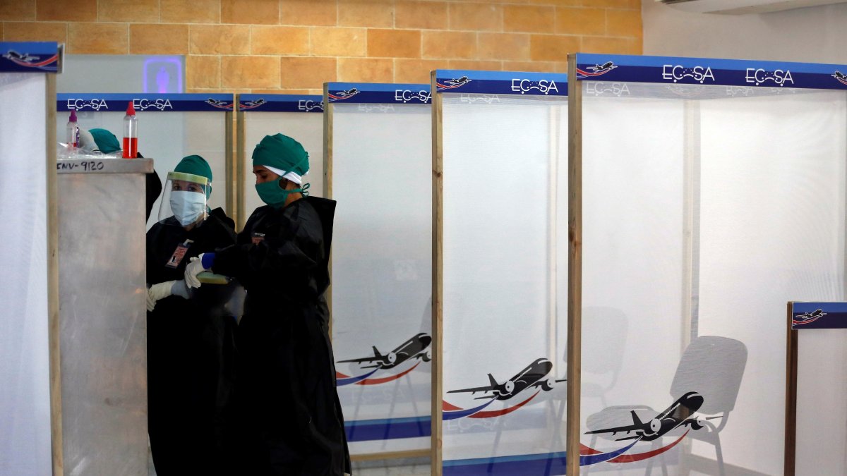 Varias personas con trajes de protección contra el coronavirus revisan el material de trabajo dentro de la zona roja en el aeropuerto internacional Jardines del Rey en Cayo Coco en Cuba.