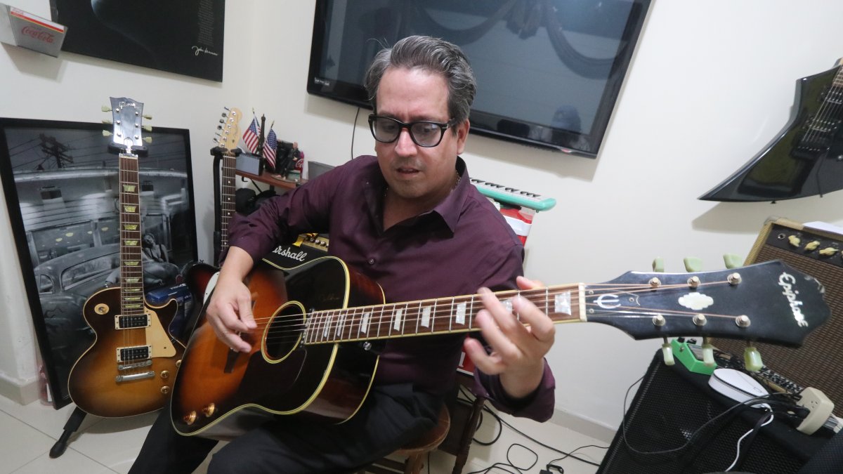 Abraham Cheing, juez y cantante en su despacho, tocando una de sus guitarras.