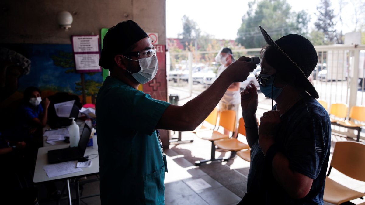 Un enfermero toma la temperatura a una mujer antes de su ingreso a un centro de salud en Santiago (Chile).