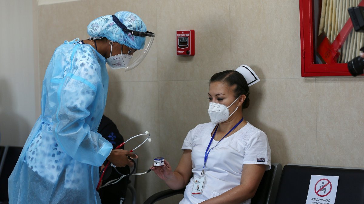 Una enfermera revisa el estado de su colega Cristina Chango recibe luego de ser vacunada contra la covid-19 en el Hospital Centinela Pablo Arturo Suárez hoy, en Quito (Ecuador).