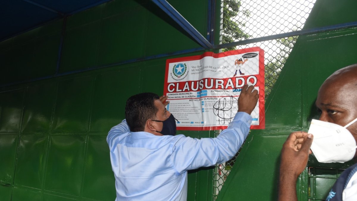 El director de Justicia y Vigilancia, Xavier Narváez, procede a colocar los sellos de clausura en la puerta del colegio Balandra.
