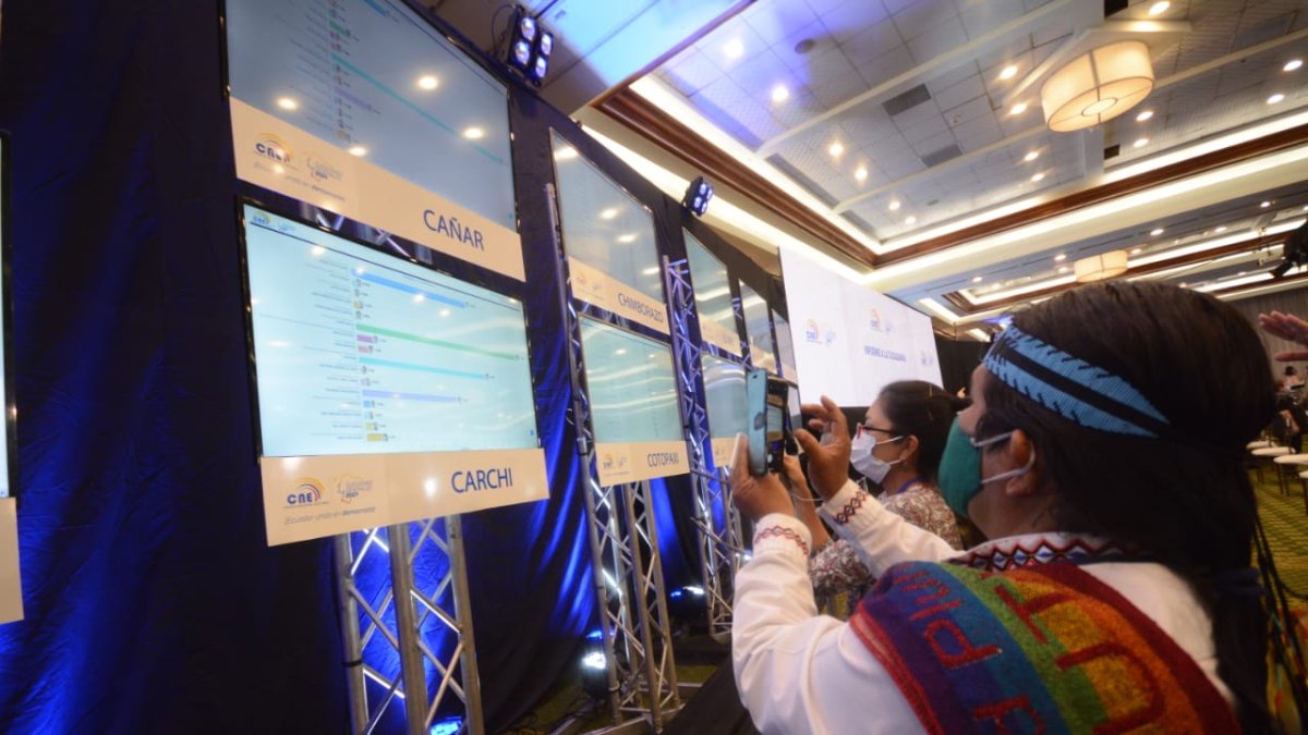 El dirigente de Pachakutik, Marlon Santi, toma una fotografía con su celular de los primeros resultados publicados.