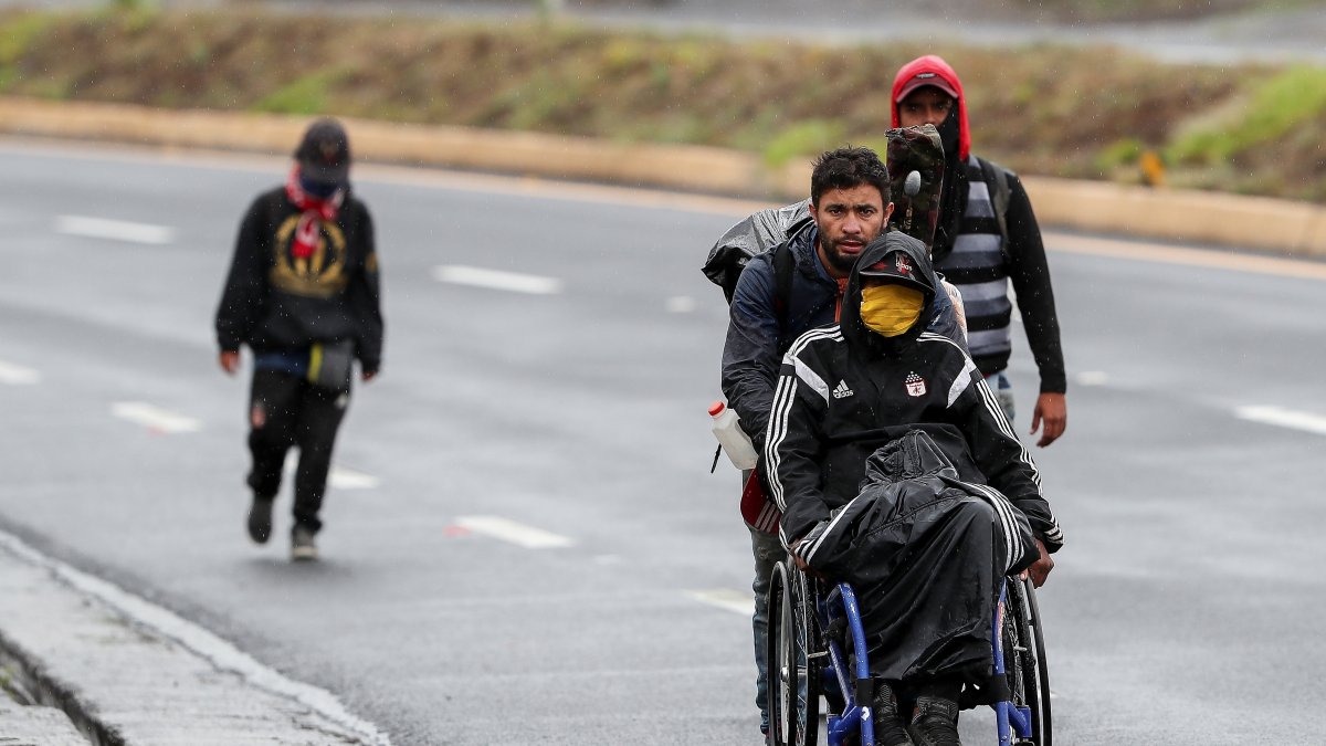Ciudadanos venezolanos, uno de ellos con discapacidad, transitan por una carretera cercana a Quito (Ecuador).