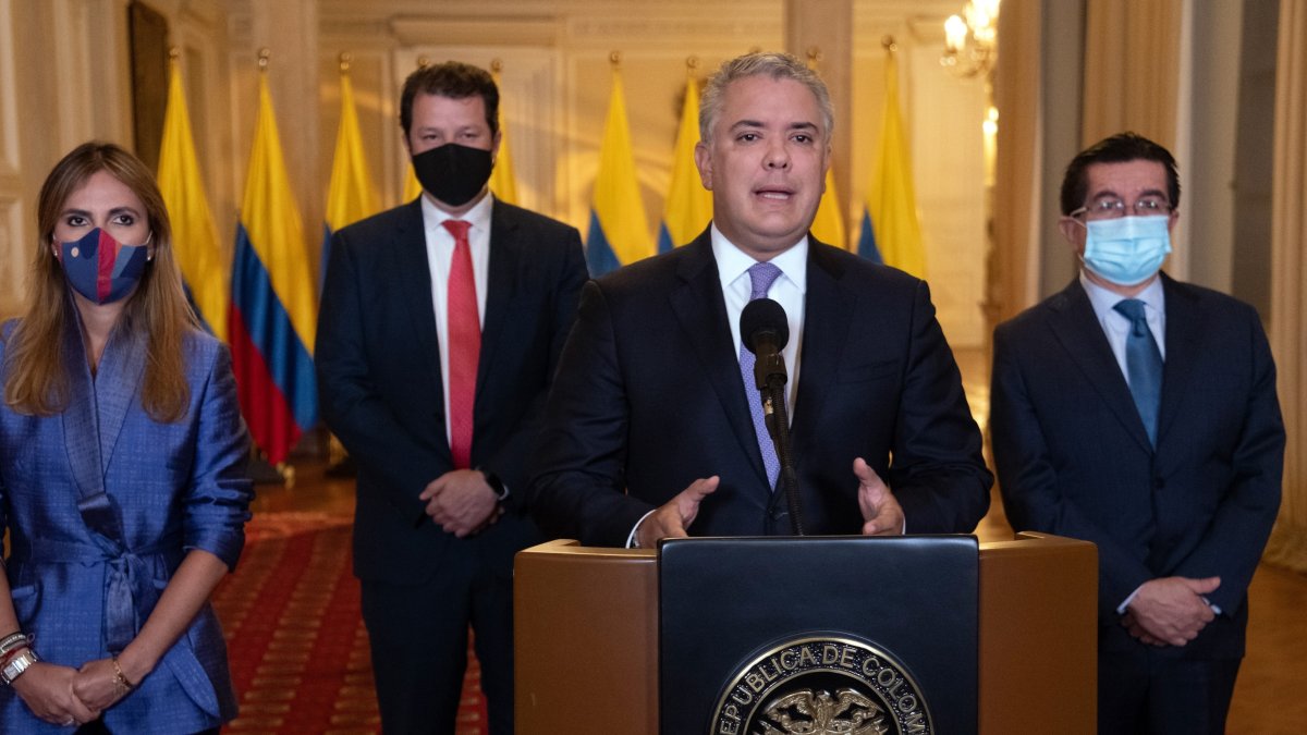 Iván Duque (2d), acompañado por el ministro de Salud, Fernando Ruiz (d), mientras anuncia la llegada del primer cargamento de vacunas.
