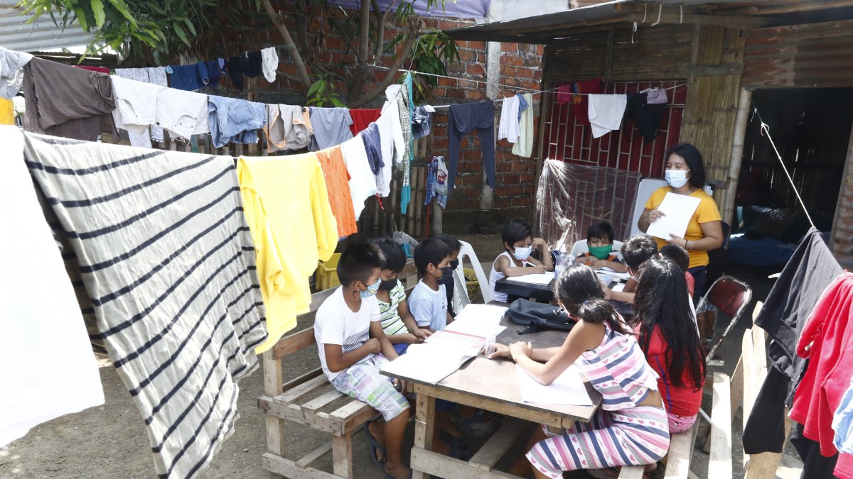 La ropa tendida en los cordeles, topa las cabezas de los niños que acuden al patio de una casa a realizar sus tareas escolares.