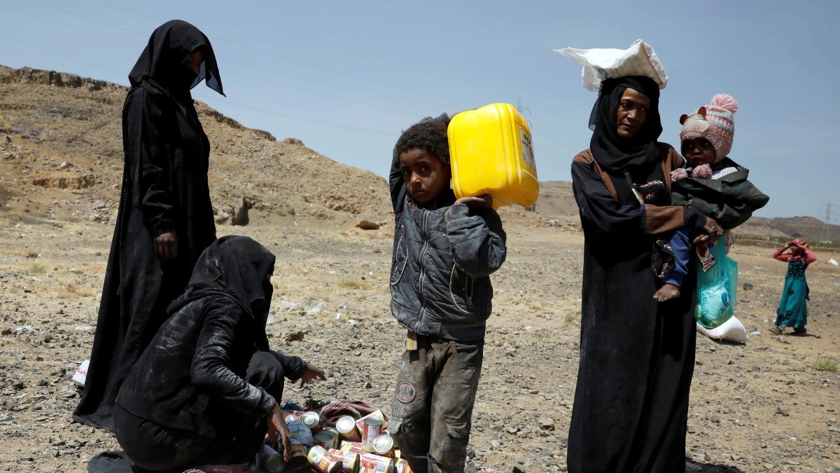Yemeníes desplazados llevan sus raciones de alimentos proporcionadas por Mona Relief Yemen antes de una conferencia internacional de donantes sobre Yemen.