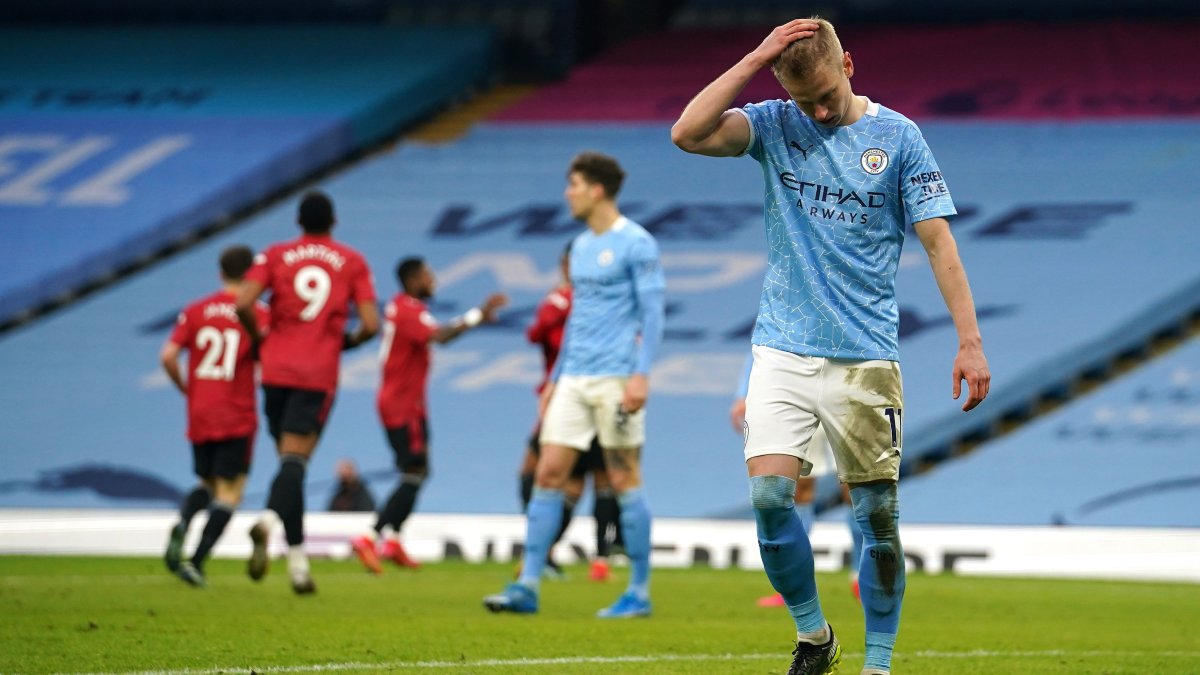 Oleksandr Zinchenko del Manchester City se lamenta, mientras al fondo celebran los jugadores del United.
