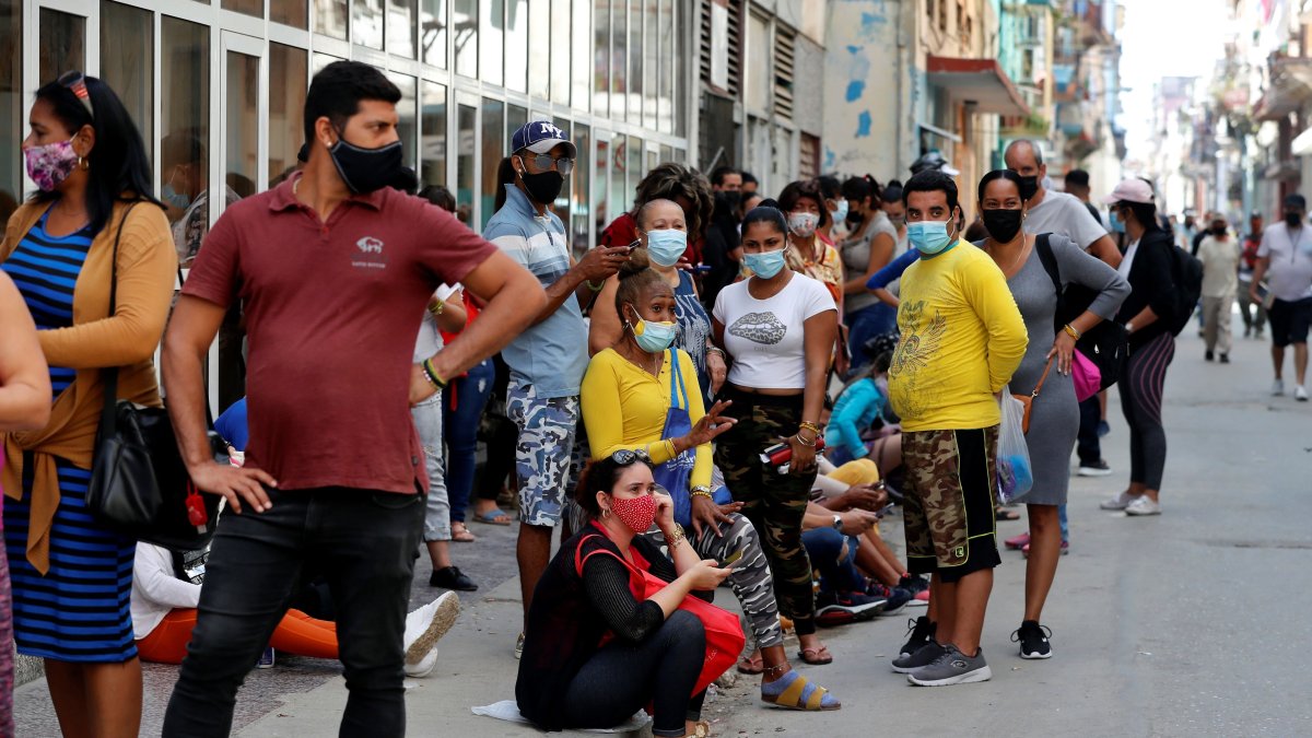 Grupos de personas con tapabocas hacen fila para comprar en un mercado, el 11 de marzo de 2021, en La Habana (Cuba).
