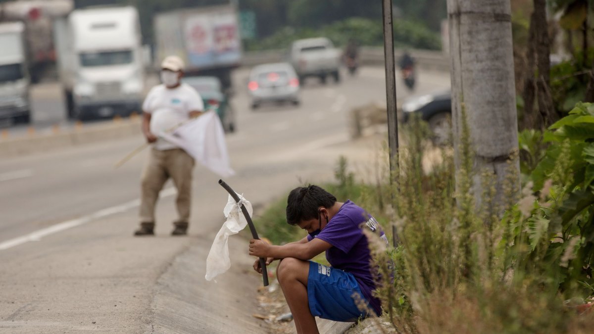 Un niño ondea una bandera blanca en la carretera pidiendo ayuda por hambre.