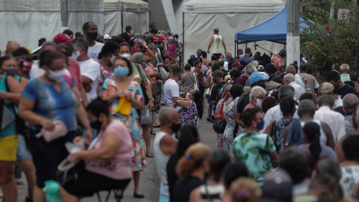 Grupos de personas hacen fila para recibir la vacuna contra la Covid-19 hoy, en la ciudad de Duque de Caxias (Brasil).