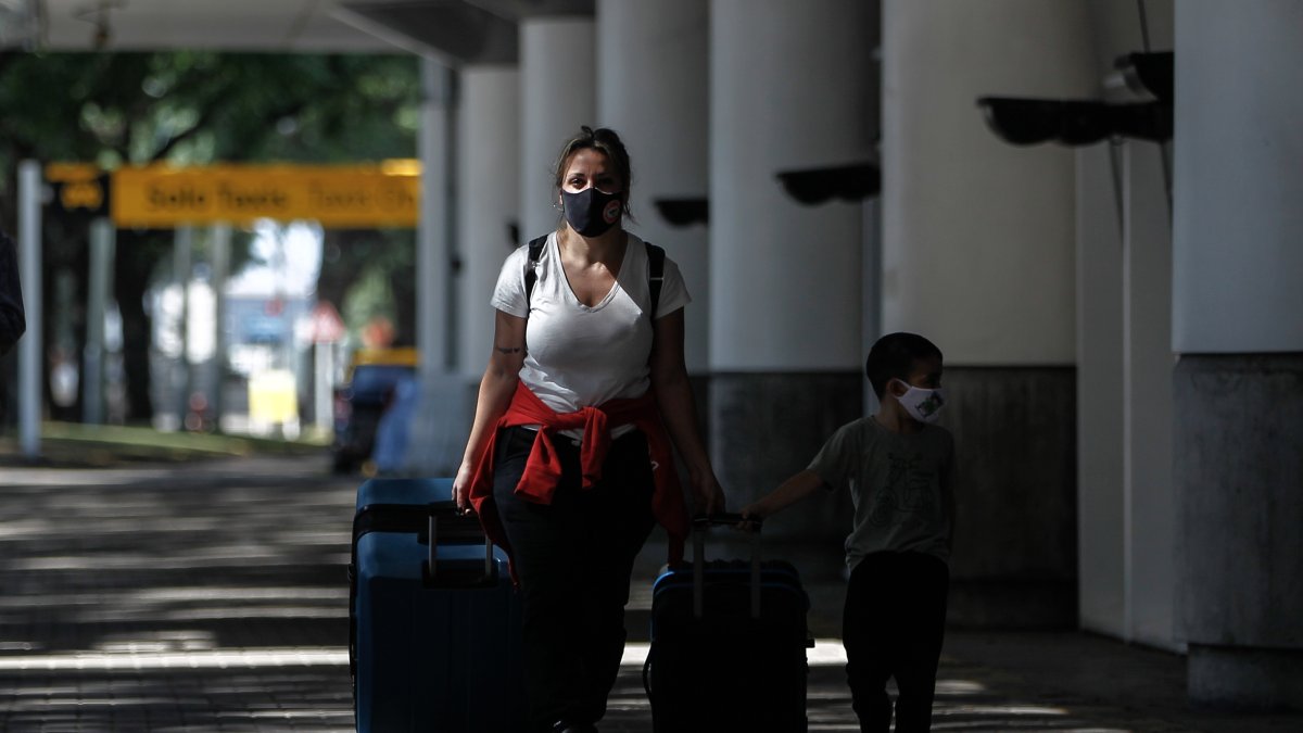 AME6722. BUENOS AIRES (ARGENTINA), 30/03/2021.- Grupos de personas caminan hoy, por el aeropuerto de Buenos Aires (Argentina). Argentina cierra por completo sus fronteras terrestres y restringe vuelos internacionales para frenar la llegada de las variantes de la covid-19 y enfrentar la nueva escalada de contagios, considerada ya como segunda ola, que coincide con el comienzo del otoño y el lento avance del plan de vacunación. EFE/ Juan Ignacio Roncoroni