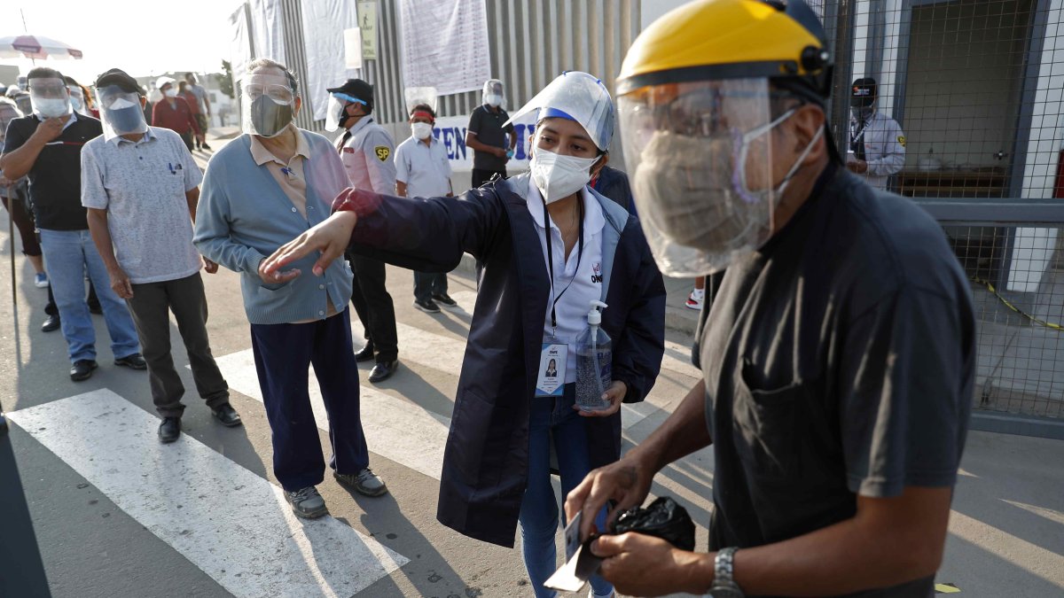 Un hombre recibe instrucciones para encontrar su puesto de votación hoy, en un colegio electoral del distrito de Villa El Salvador, en Lima.