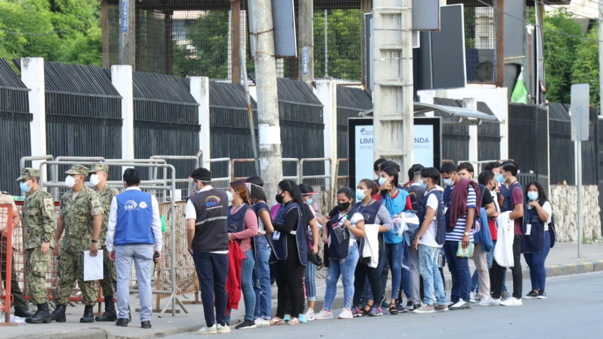Personal de la mesa del recinto electoral haciendo fila para ingresar a una institución.