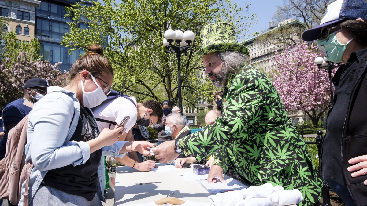 El voluntario Todd Hinden (R) reparte cigarrillos de marihuana a todo aquel que pueda demostrar que ha sido vacunado contra el COVID-19.