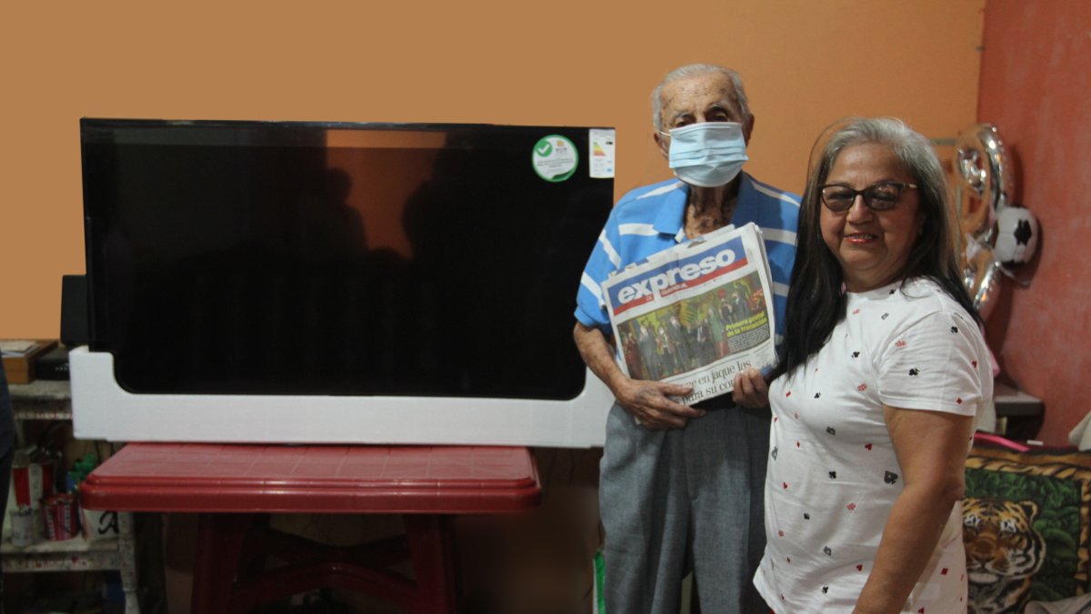 Premio. Laura junto a su padre Carlos, de 99 años, en el momento en el que recibieron el televisor en su casa.