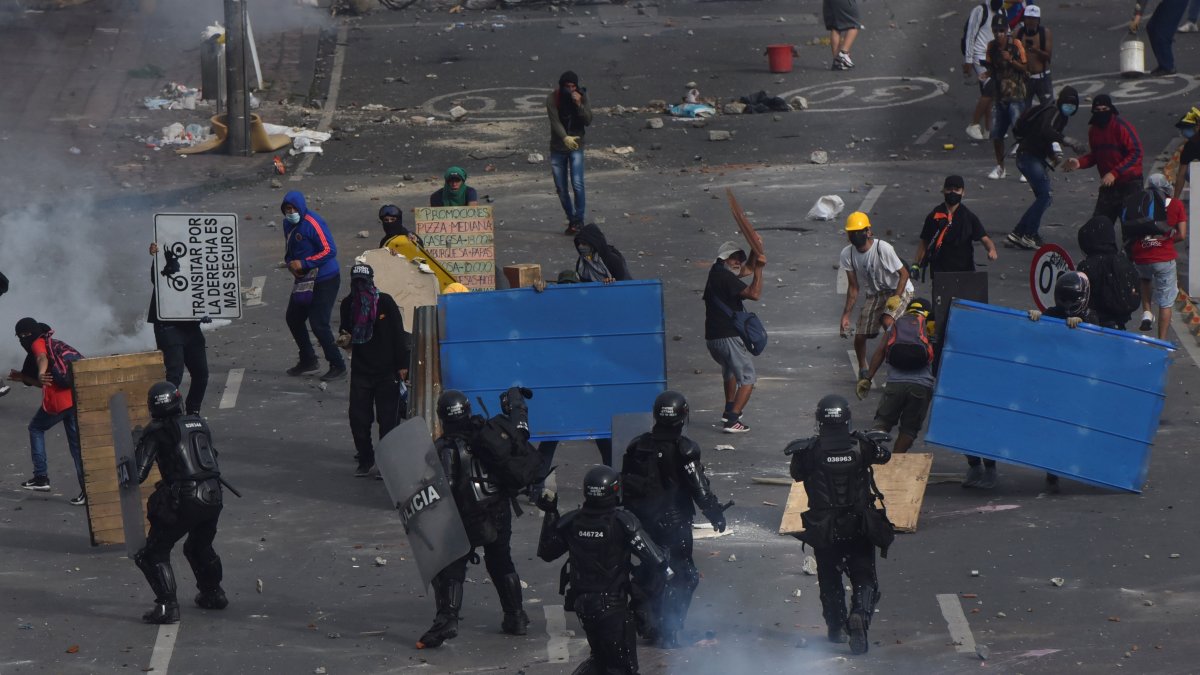 Manifestantes se enfrentan con miembros del Escuadrón Móvil Antidisturbios (ESMAD) durante las protestas hoy en Cali (Colombia).