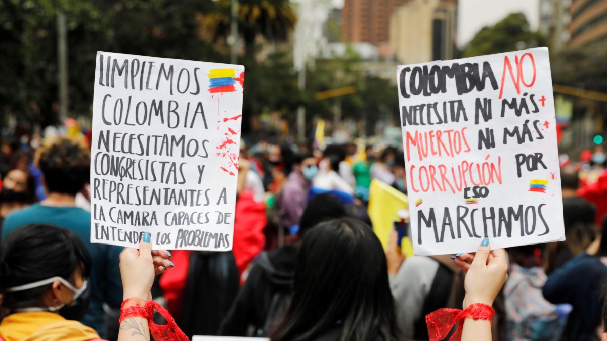 Una mujer sostiene dos carteles durante una protesta en rechazo a la violencia ocurrida en las protestas hoy, en el Parque Nacional de Bogotá (Colombia).