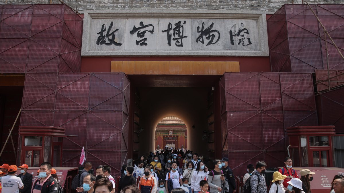 Los turistas caminan fuera de la Ciudad Prohibida en Pekín, China.