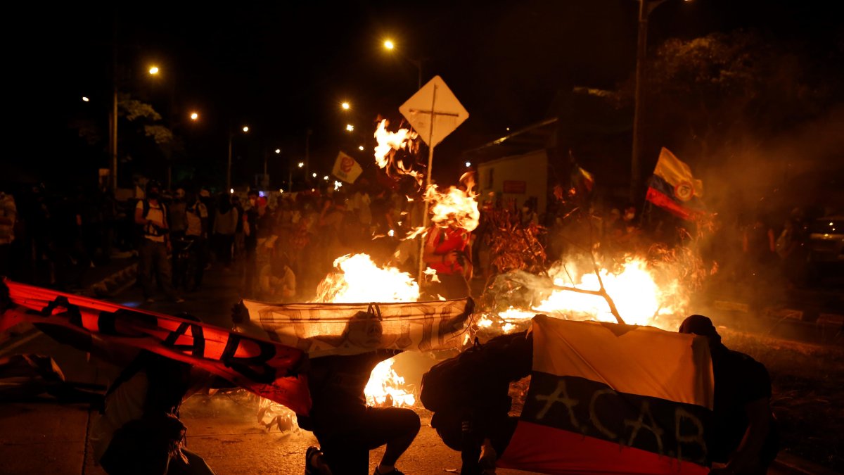 Manifestantes muestran banderas, mientras queman objetos, durante una manifestación contra del gobierno de Iván Duque, este lunes, en Cali (Colombia).