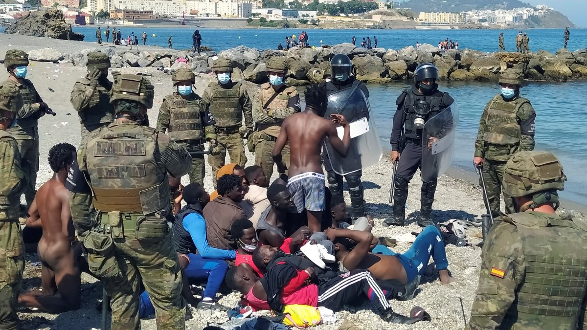 Miembros del Ejército de Tierra y de la Cruz Roja ayudan a un inmigrante que han logrado cruzar uno de los espigones fronterizos de Ceuta.