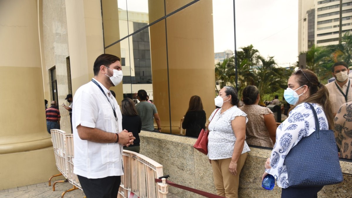 El coordinador Zonal 8 del Registro Civil, Andrés Fantoni Baldeón, habla con usuarios que hacen fila para sacar el pasaporte en Guayaquil.