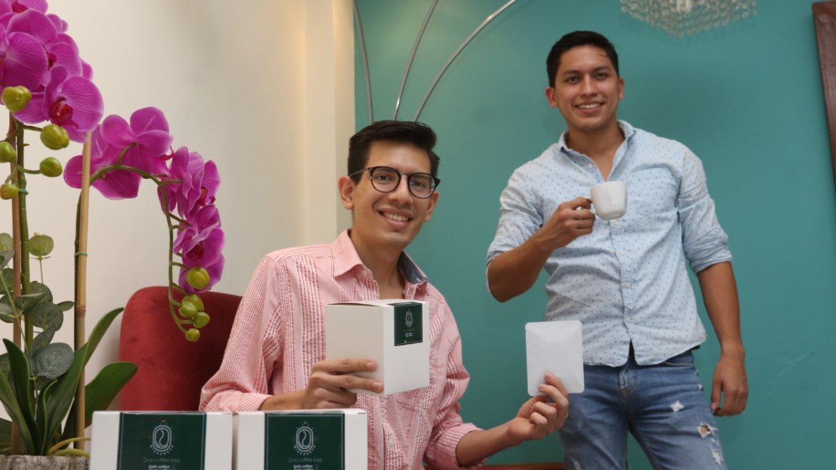 Josué y Pepe posan y muestran su emprendimiento de café para filtrar.