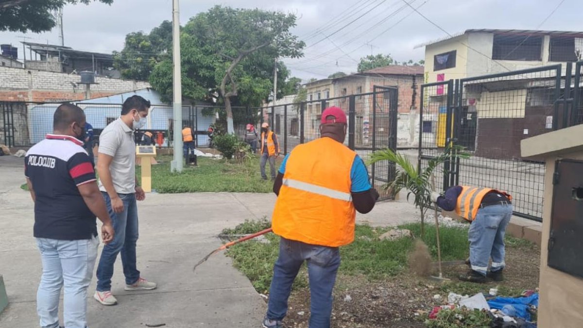 Moradores y policías limpian las aceras de un parque en el Guasmo sur de Guayaquil.