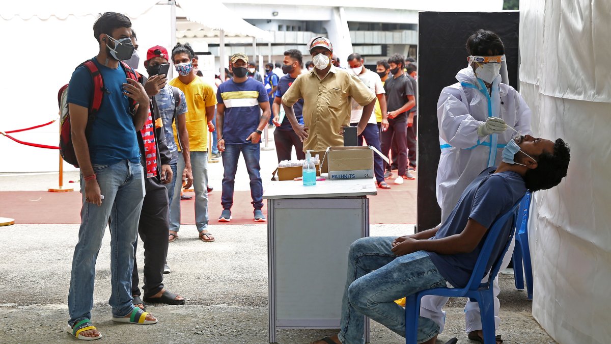 Un trabajador de salud toma una muestra nasal y un hisopo de un hombre para una prueba de COVID-19 en Bangalore, India.