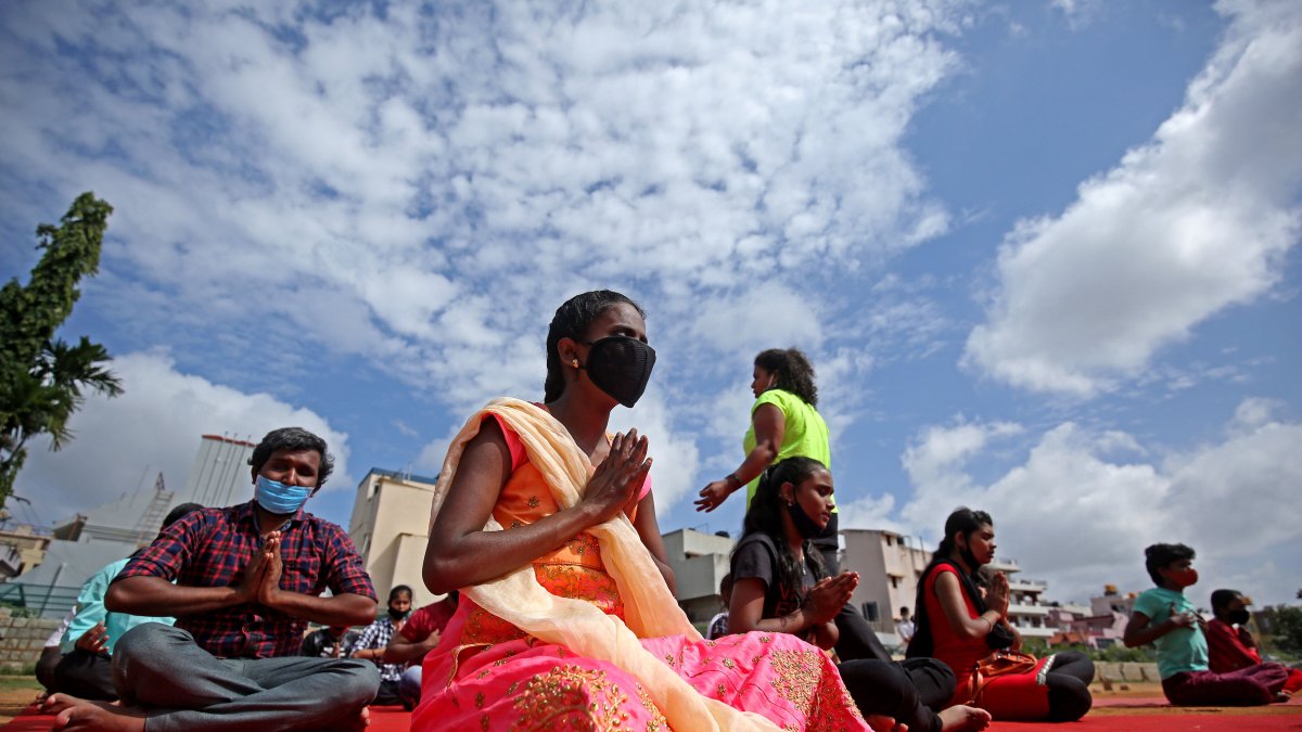 Niños con discapacidades visuales y entusiastas del yoga que usan mascarillas practican la meditación en el Día Internacional del Yoga en Bangalore, India.