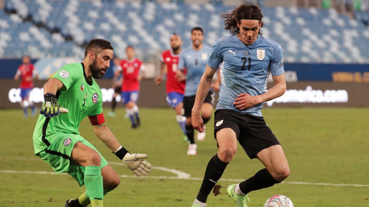 Claudio Bravo, arquero de Chile, trata de obstaculizar una acción de Edinson Cavani, delantero uruguayo.