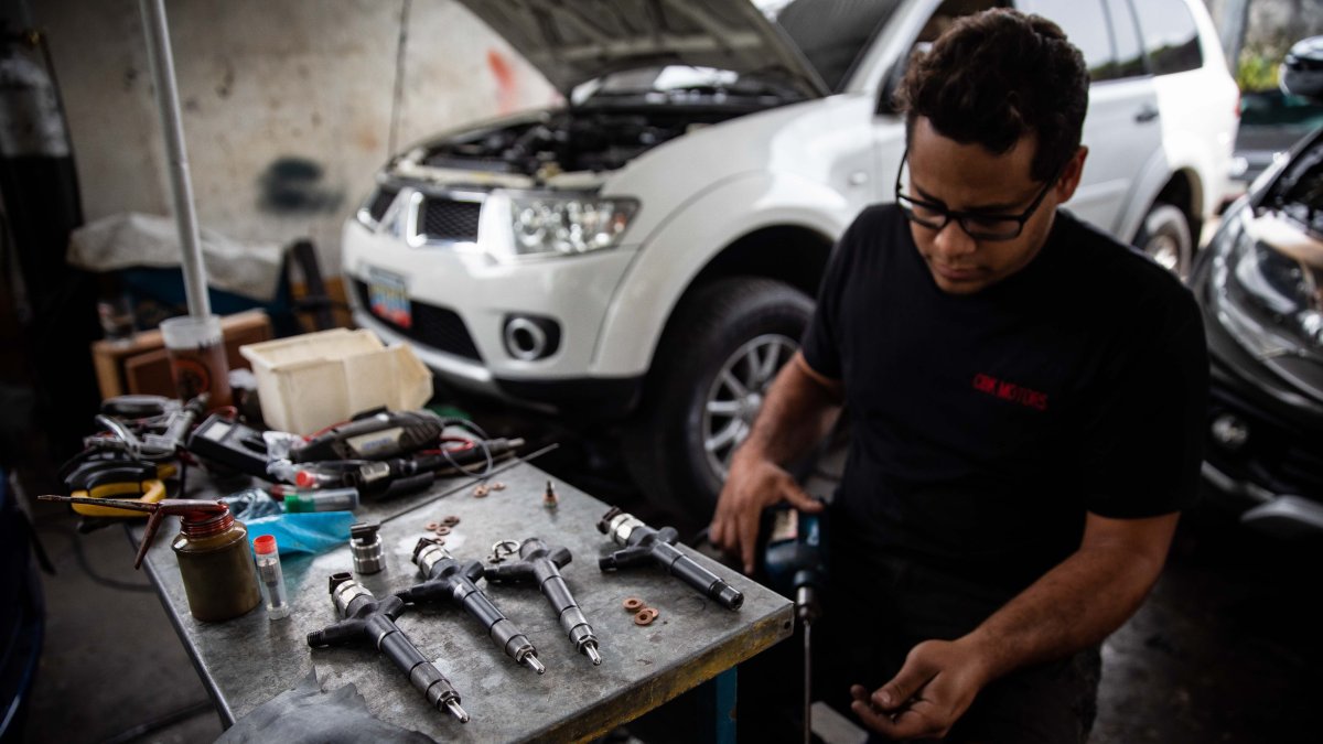 El mecánico, Ruben Requeana, repara una pieza de los inyectores de un vehículo, el 17 de junio, en Caracas (Venezuela).
