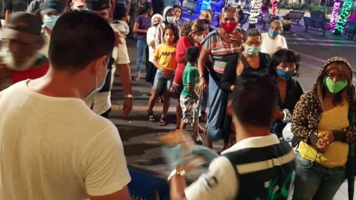 Jóvenes profesionales reparten los víveres a las personas que habitan en la calle.