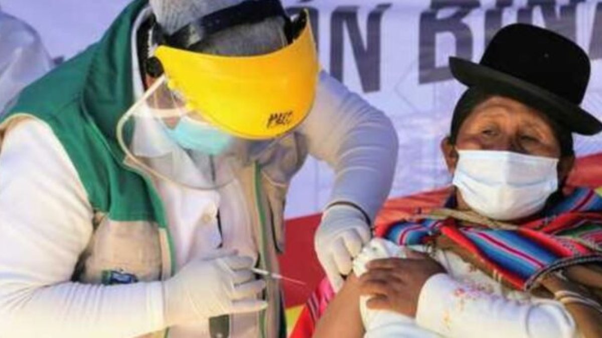 Un médico vacuna a una indígena boliviana.