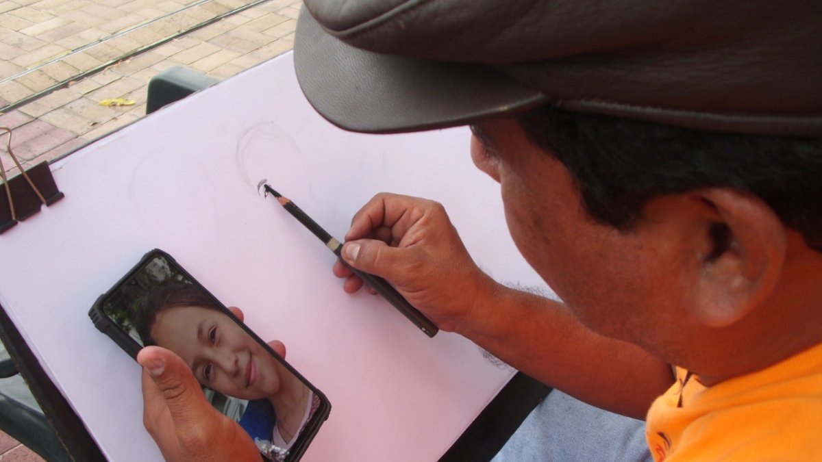 Édgar Jaime pintando un retrato que una cliente le envió por Whatsapp, en estos tiempos de pandemia.