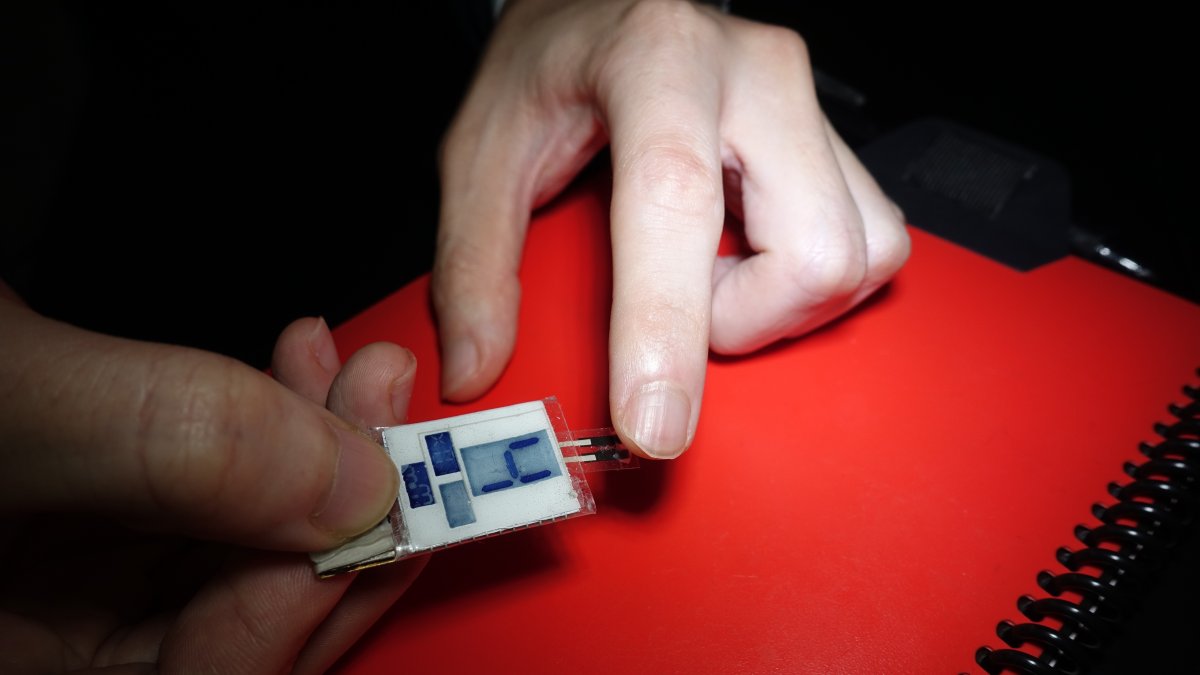 Un pequeño hidrogel (a la derecha) que recoge el sudor de la yema del dedo para el sensor de vitamina C (a la izquierda), y luego muestra el resultado en la pantalla.