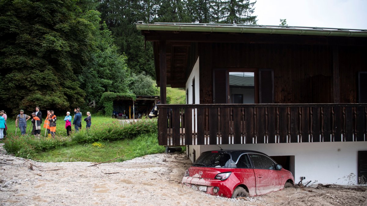 Un coche aparece semienterrado por las inundaciones en Schoenau am Koenigssee, Alemania.