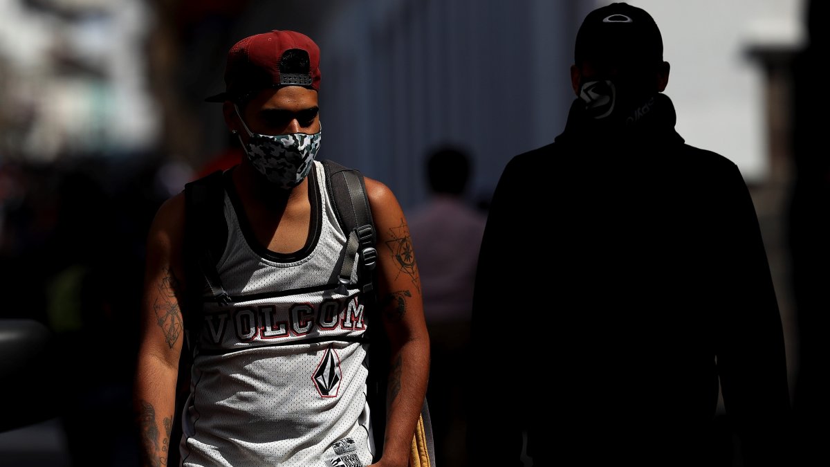 En la imagen, un hombre con mascarilla camina por una calle de Quito (Ecuador).