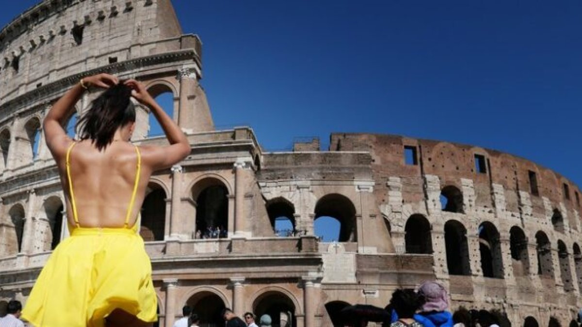 Una turista con ropa ligera visita el Coliseo Romano.
