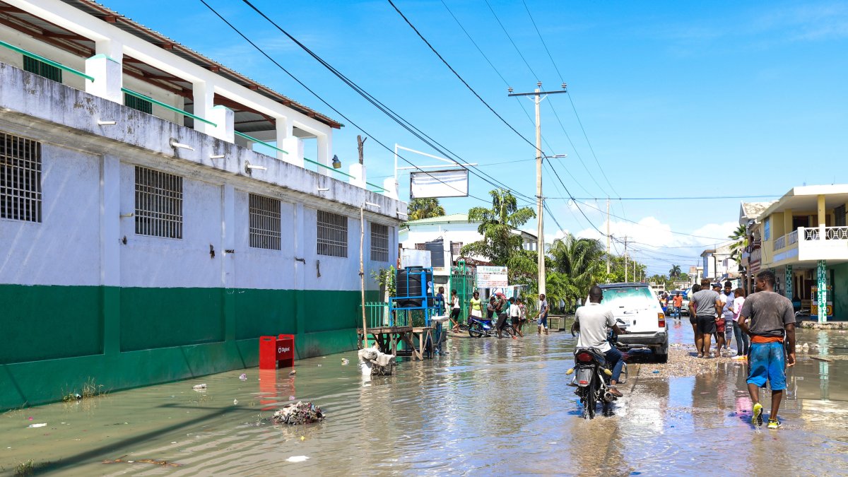Grupos de personas transitan por una calle inundada tras un seísmo de 7,2 grados hoy, en Los Cayos (Haití).
