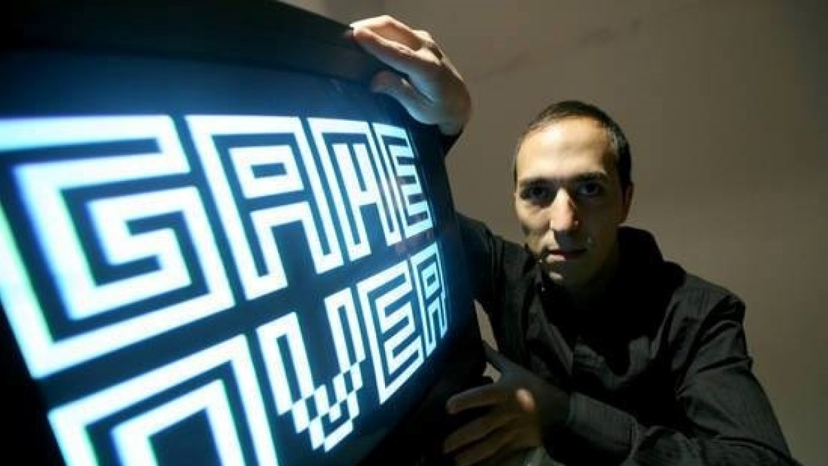 Fotografía cedida por el artista Yucef Merhi en la que aparece mientras posa junto a una de sus obras.