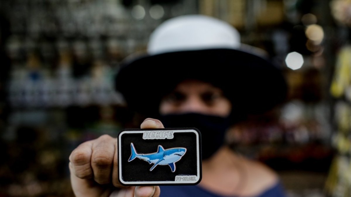 Una turista muestra un imán con la imagen de un tiburón, el 12 de agosto de 2021, en Jaboatao dos Guararapes (Brasil).