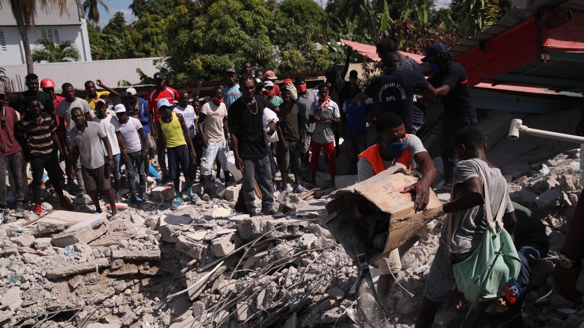 Un grupo de personas remueve escombros en una calle de Los Cayos.