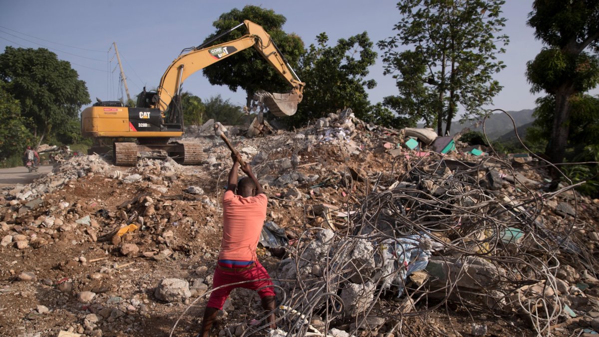 Un hombre recupera varillas de hierro para reutilizar en una área llena de escombros por la caída de un muro durante el terremoto . EFE/ Orlando Barría