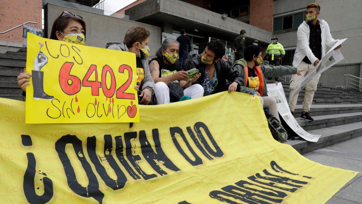 Una mujer muestra un cartel que detalla el número 6.402, cifra aludida a las víctimas de los llamados 