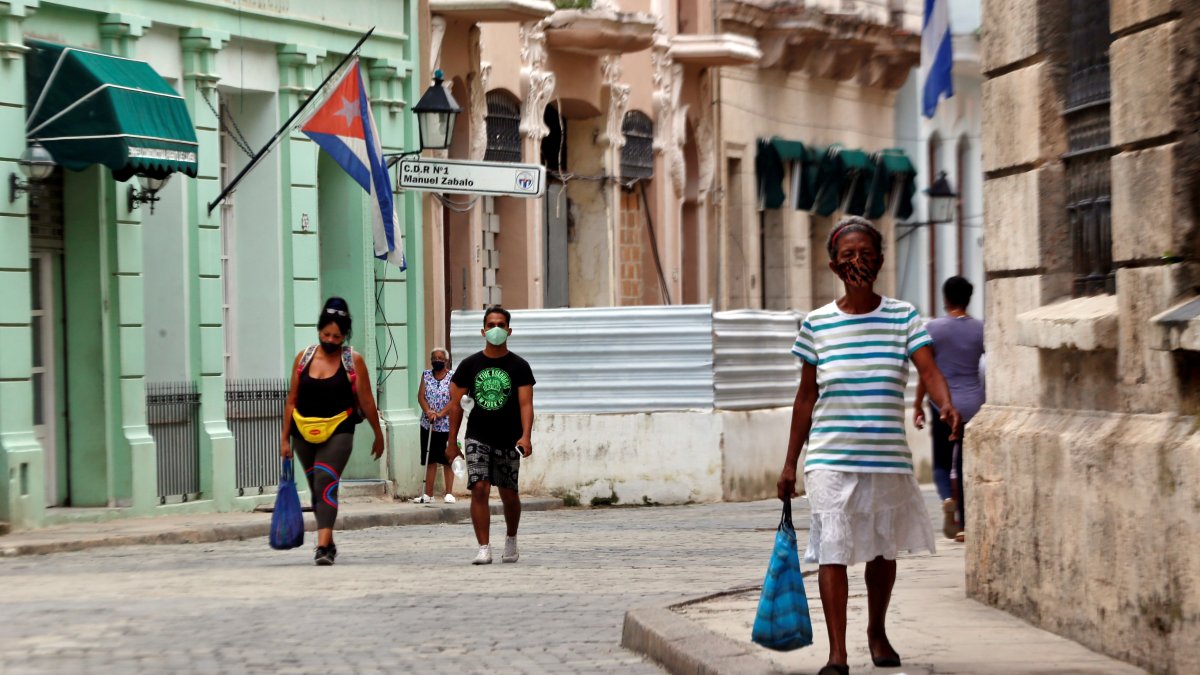 Varias personas con tapabocas caminan por una calle, en La Habana (Cuba).